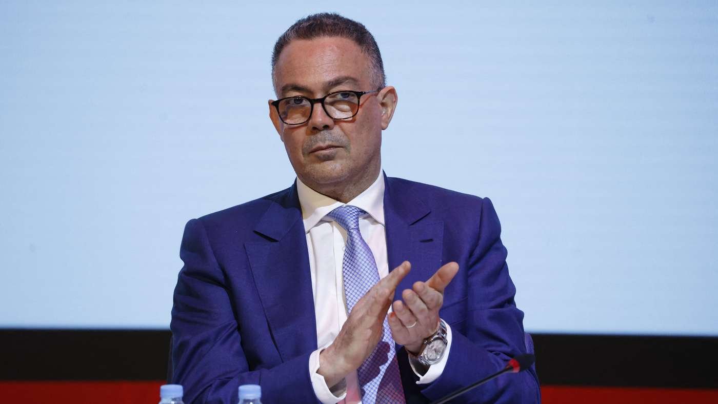 Man in a blue suit and glasses clapping at a panel discussion Man in a blue suit and glasses clapping at a panel discussion