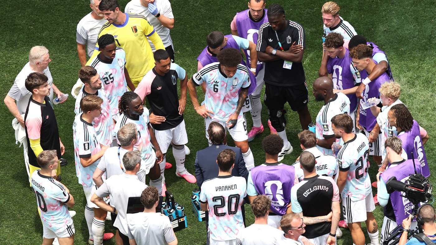 Soccer team huddle on a green field, players gathered around a coach giving instructions during a break. Soccer team huddle on a green field, players gathered around a coach giving instructions during a break.