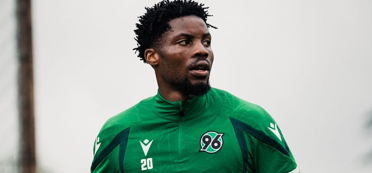 Male footballer in a bright green training jacket with a team crest '96' and the number 20. Male footballer in a bright green training jacket with a team crest '96' and the number 20.