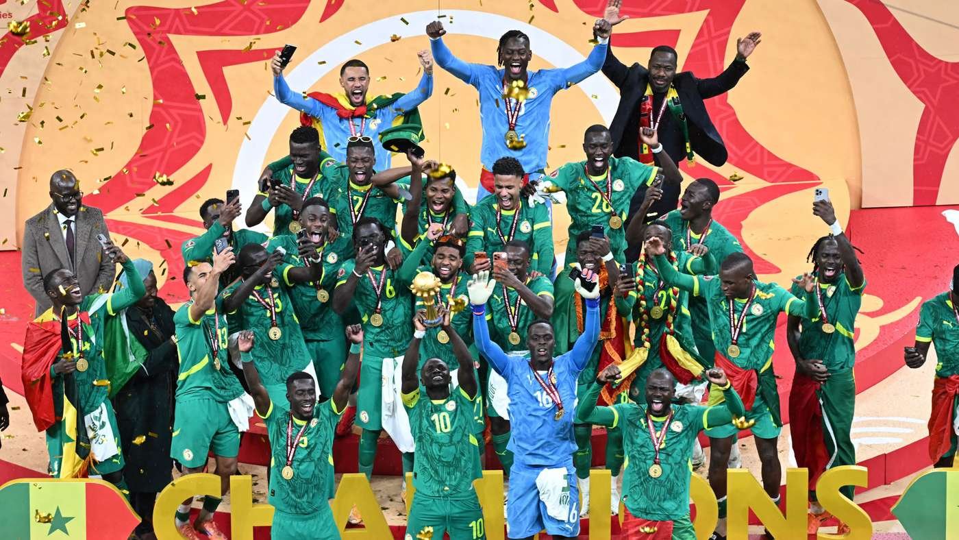 Senegalese football team celebrating on a podium with medals, green uniforms, blue goalkeeper, and confetti during a victory ceremony Senegalese football team celebrating on a podium with medals, green uniforms, blue goalkeeper, and confetti during a victory ceremony