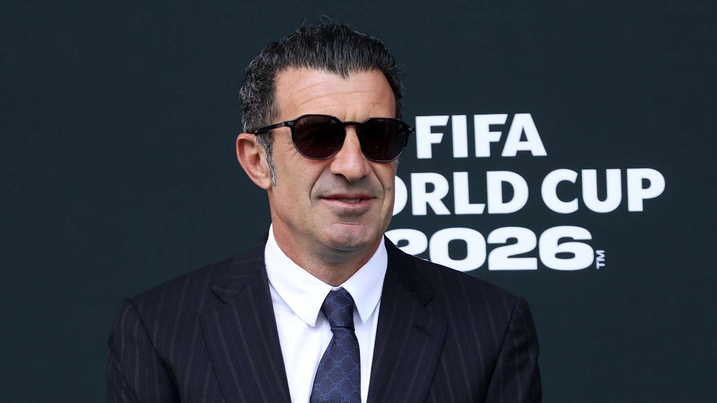 Man in a pinstripe suit and dark sunglasses stands before a FIFA World Cup 2026 backdrop.