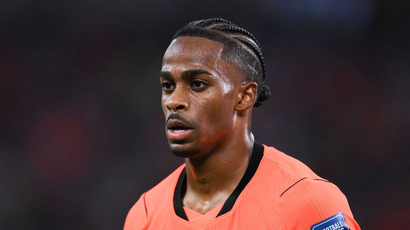 Close-up of a male football player with braided hair, sweating, wearing an orange jersey on the field. Close-up of a male football player with braided hair, sweating, wearing an orange jersey on the field.