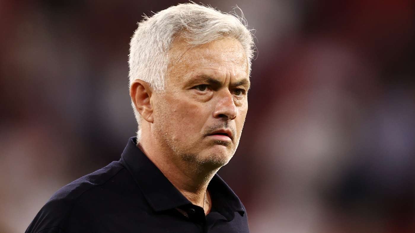 Close-up of a mature man with gray hair in a black polo, looking serious on the sidelines. Close-up of a mature man with gray hair in a black polo, looking serious on the sidelines.