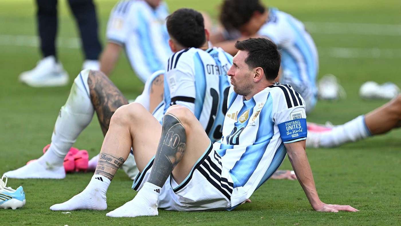 Argentinian soccer players sit on the green field in light blue and white striped kits, resting after training. Argentinian soccer players sit on the green field in light blue and white striped kits, resting after training.