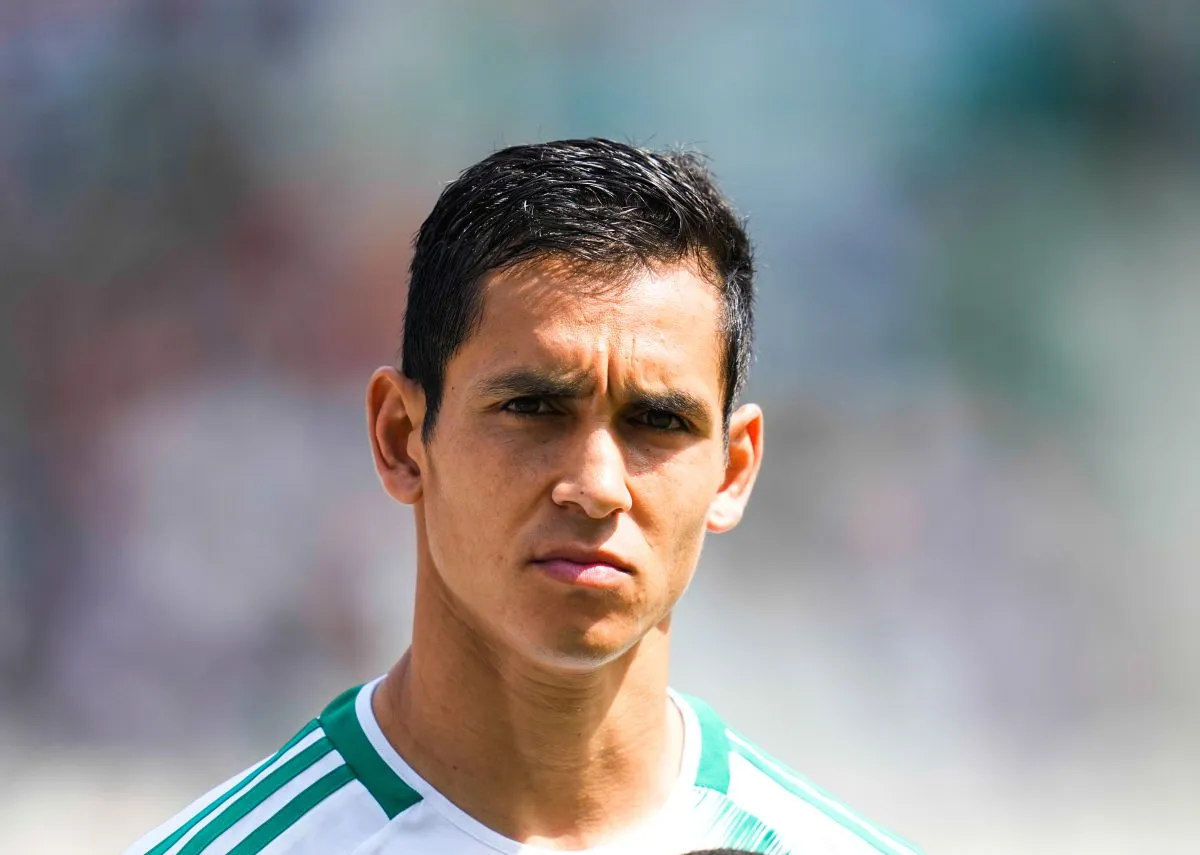 Soccer player with short black hair wearing a green-and-white jersey, looking focused ahead