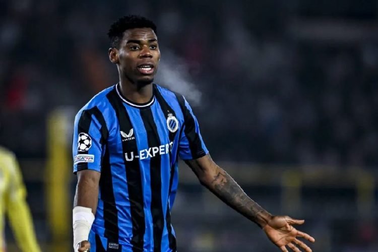 Footballer in blue-and-black striped kit on the pitch, gesturing with his arm during a match. Footballer in blue-and-black striped kit on the pitch, gesturing with his arm during a match.