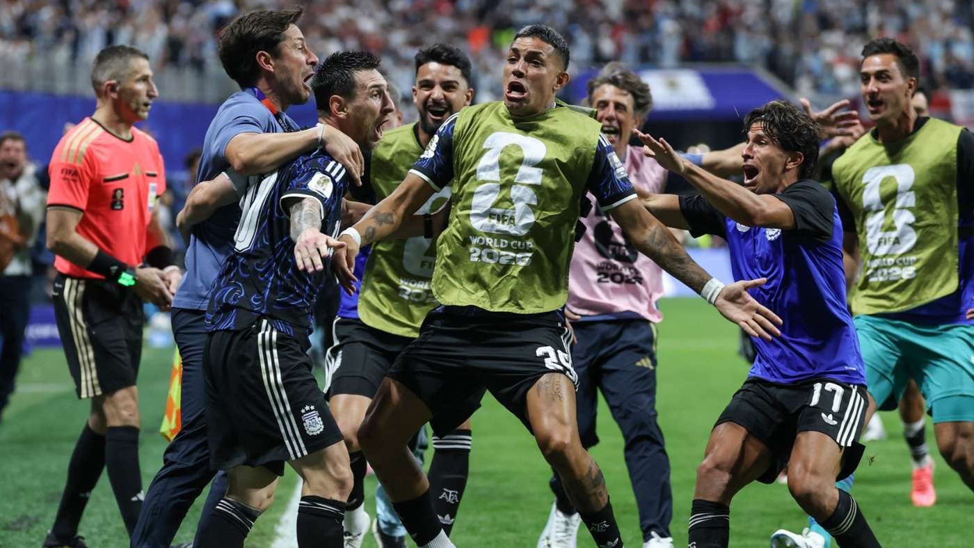 Soccer players in green bibs celebrate on the field, arms around each other after a match, with a crowd in the stands behind them. Soccer players in green bibs celebrate on the field, arms around each other after a match, with a crowd in the stands behind them.