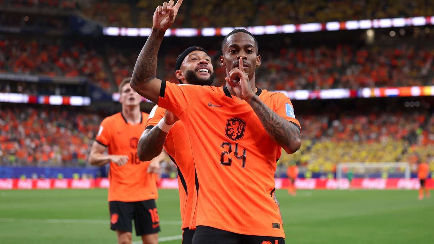 Dutch soccer players celebrate on the field in orange kits; foreground player with #24 makes a shushing gesture. Dutch soccer players celebrate on the field in orange kits; foreground player with #24 makes a shushing gesture.