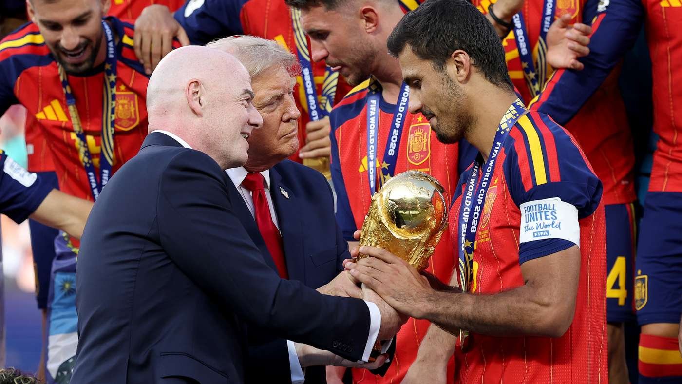 Spain football team celebrate as a player in red receives the golden World Cup trophy from officials.