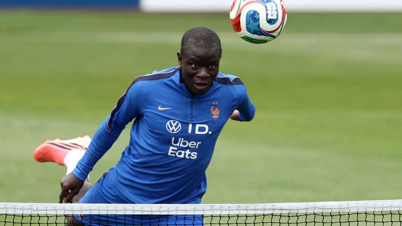 Soccer player in a blue kit jumps near the goal, eyes on a ball overhead as he prepares to head it. Soccer player in a blue kit jumps near the goal, eyes on a ball overhead as he prepares to head it.