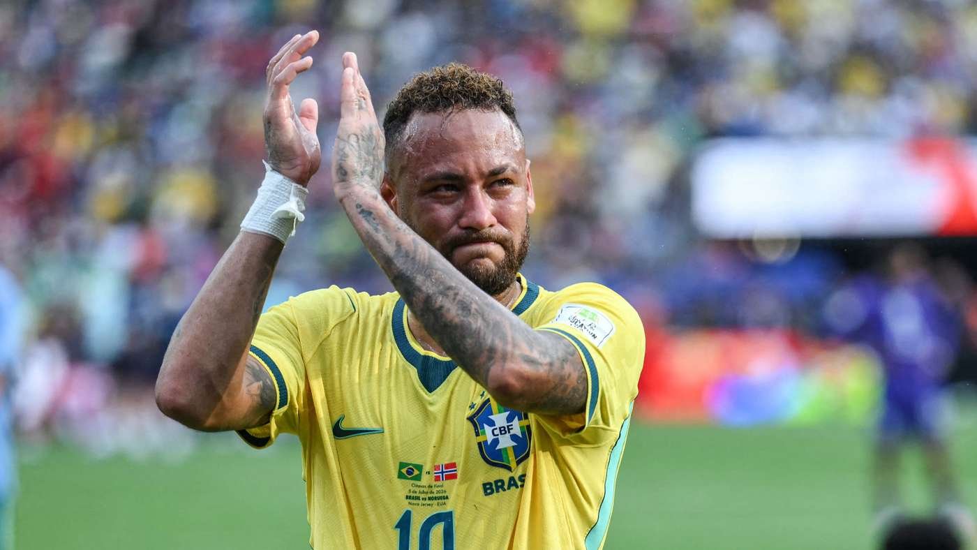 Brazilian footballer in a yellow Brazil jersey applauding on the field, clapping with tattooed arms visible. Brazilian footballer in a yellow Brazil jersey applauding on the field, clapping with tattooed arms visible.