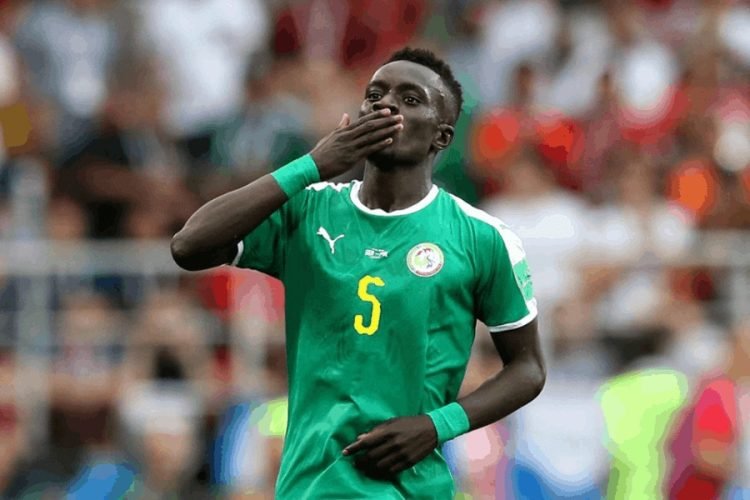 Soccer player wearing a green jersey with the number 5 blowing a kiss to the crowd on the pitch.