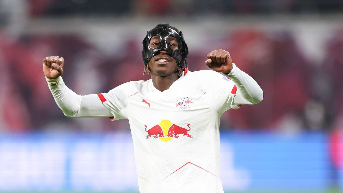 Soccer player in a white kit with Red Bull logo celebrating with fists raised.