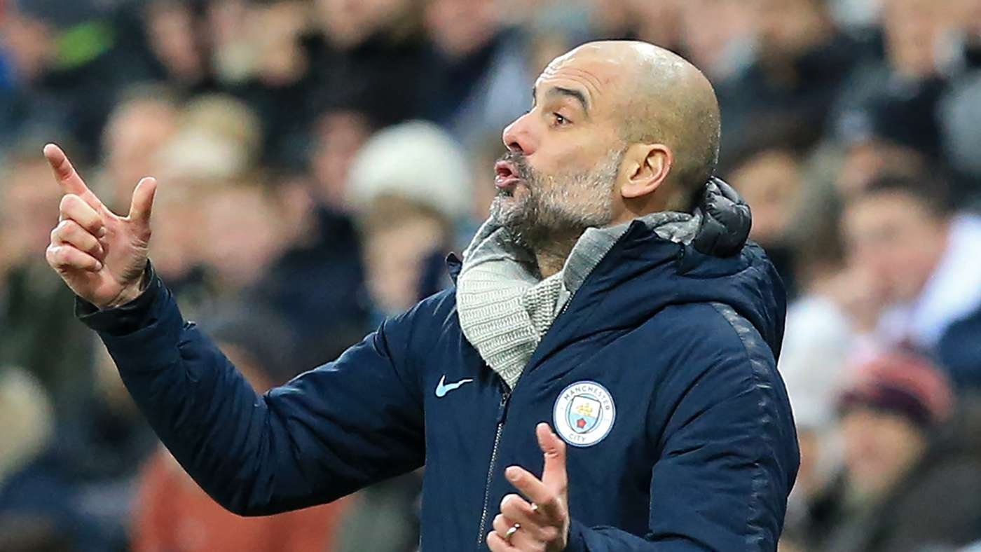 Pep Guardiola on the touchline, pointing and giving instructions, wearing a navy Manchester City jacket and scarf. Pep Guardiola on the touchline, pointing and giving instructions, wearing a navy Manchester City jacket and scarf.