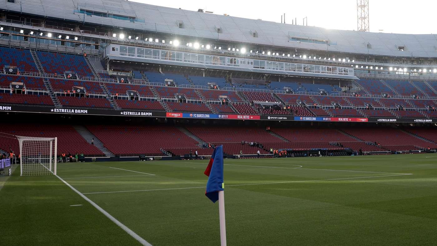 Soccer stadium with green pitch, corner flag in foreground and empty red seating around the field. Soccer stadium with green pitch, corner flag in foreground and empty red seating around the field.