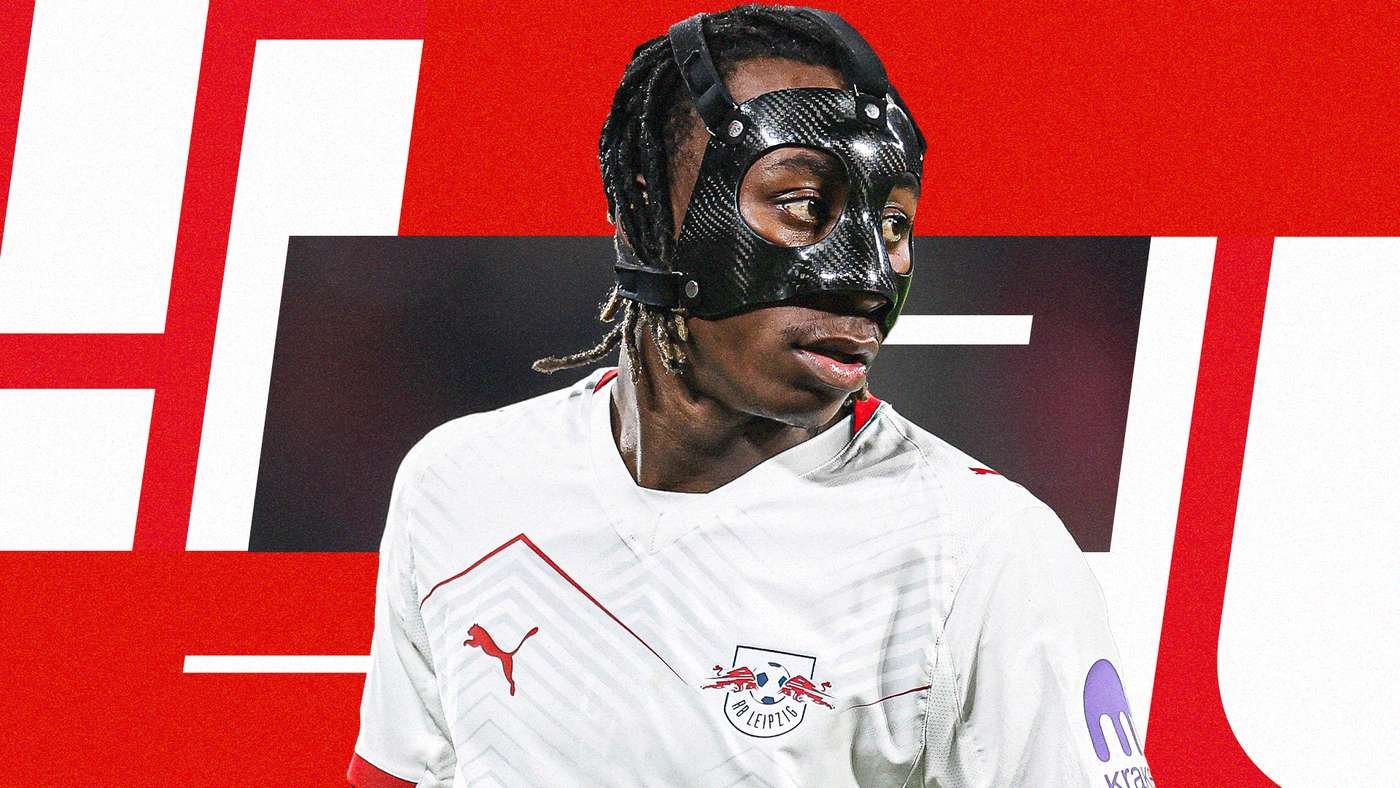Footballer in a black protective mask and white RB Leipzig jersey, looking to the side, against a red abstract background. Footballer in a black protective mask and white RB Leipzig jersey, looking to the side, against a red abstract background.