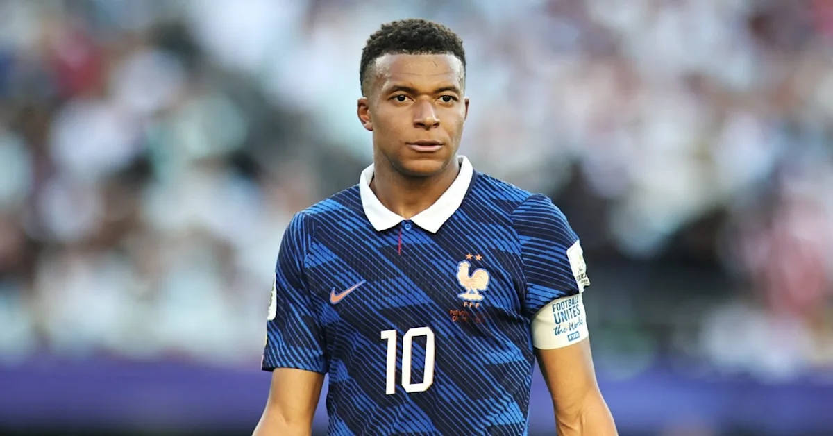 French national team footballer in a blue kit with number 10 on the chest, standing on the pitch during a match with blurred crowd behind him. French national team footballer in a blue kit with number 10 on the chest, standing on the pitch during a match with blurred crowd behind him.