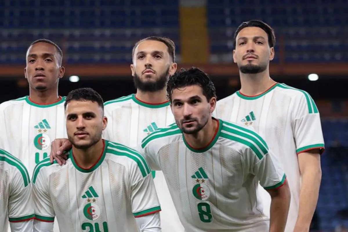 Algerian national football team players pose for a group photo in white jerseys with green accents on a stadium field