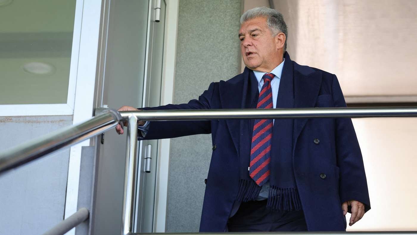 Older man in a navy coat and red striped tie stands on a balcony, gripping a metal railing. Older man in a navy coat and red striped tie stands on a balcony, gripping a metal railing.