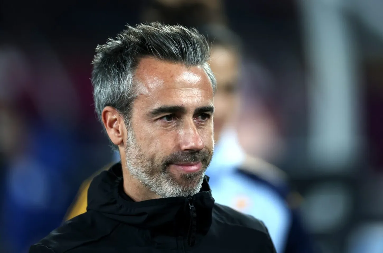 Close-up of a middle-aged man with salt-and-pepper hair and beard, wearing a black zip-up jacket, looking to the left. Close-up of a middle-aged man with salt-and-pepper hair and beard, wearing a black zip-up jacket, looking to the left.