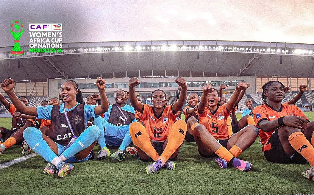 Group of female football players sitting on the pitch with fists raised in celebration; orange and blue kits, stadium backdrop, CAF Women's Africa Cup of Nations Morocco 2026 logo in the top-left. Group of female football players sitting on the pitch with fists raised in celebration; orange and blue kits, stadium backdrop, CAF Women's Africa Cup of Nations Morocco 2026 logo in the top-left.