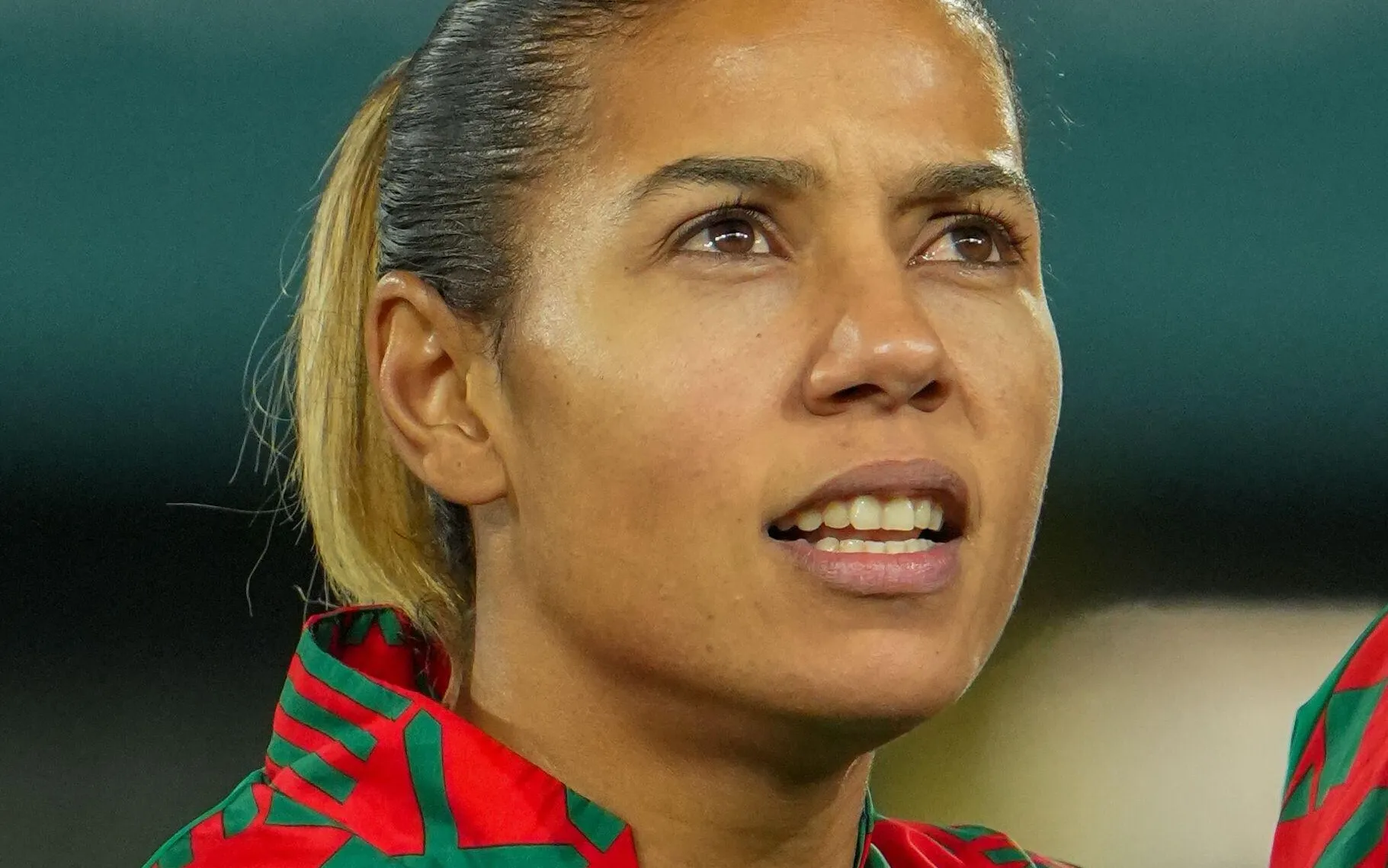 Close-up of a woman looking upward with a slight smile, wearing a red and green patterned shirt or scarf. Close-up of a woman looking upward with a slight smile, wearing a red and green patterned shirt or scarf.