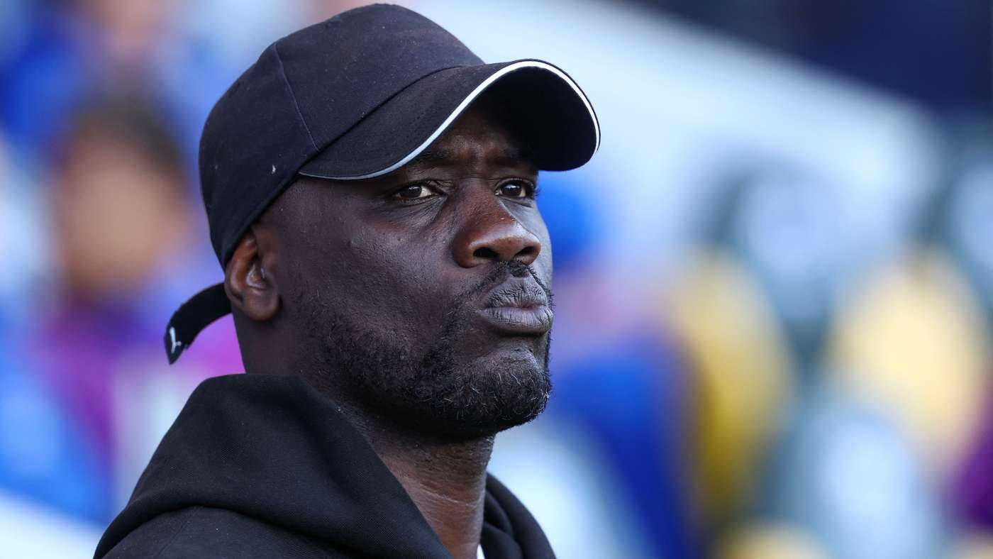 Man in a black cap and hoodie gazes upward, likely a spectator at a stadium or event.