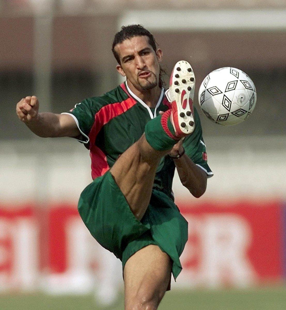 Soccer player in a green kit delivers a high kick to strike a white patterned ball midair during a match. Soccer player in a green kit delivers a high kick to strike a white patterned ball midair during a match.