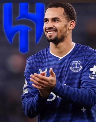 Footballer in a blue Everton kit clapping and smiling on the pitch with a large blue logo in the background Footballer in a blue Everton kit clapping and smiling on the pitch with a large blue logo in the background
