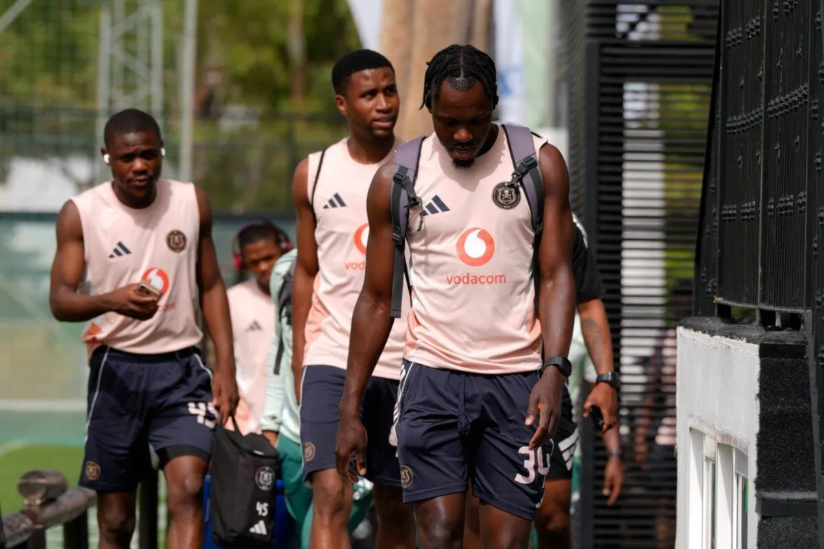 Soccer players in matching pink training jerseys walk together at a training facility, Vodafone logo visible on shirts.