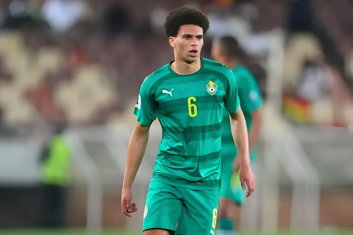 Male soccer player in a green kit with the number 6 on the chest, walking on the pitch during a match.