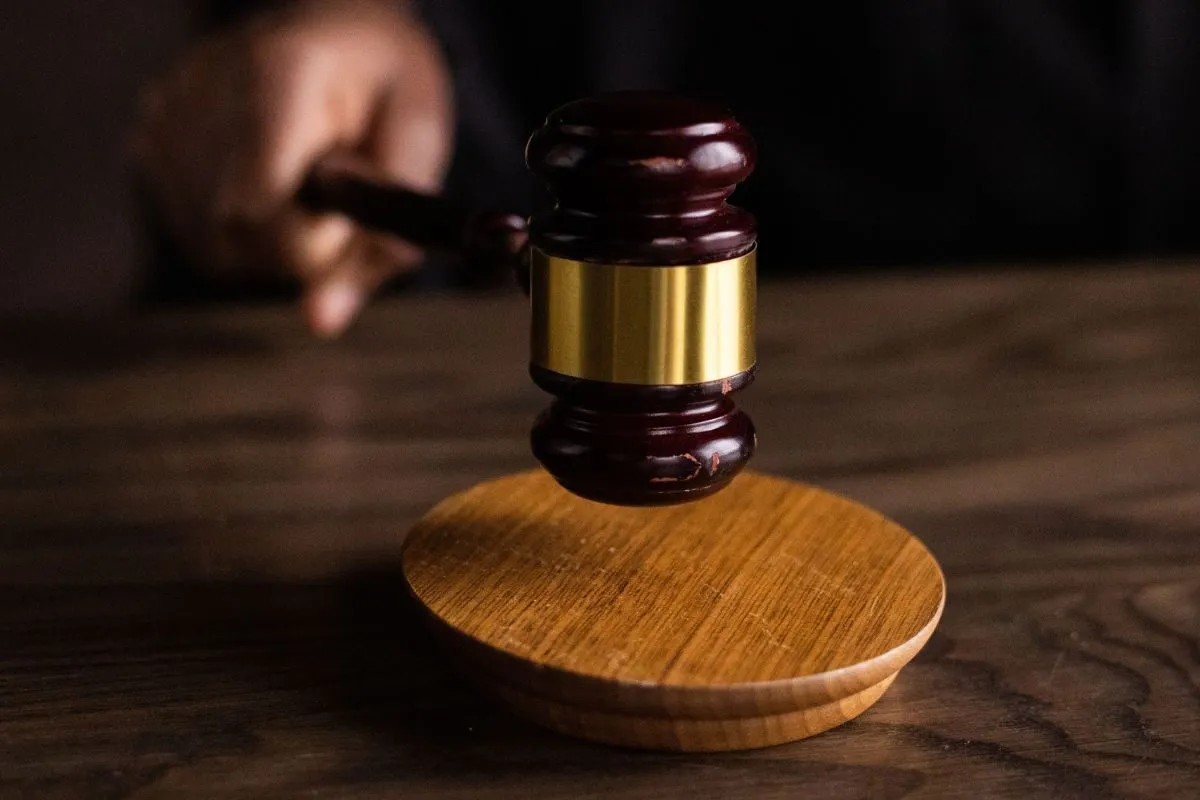 Judge's gavel mid-swing above a wooden sound block, conveying a legal ruling moment. Judge's gavel mid-swing above a wooden sound block, conveying a legal ruling moment.