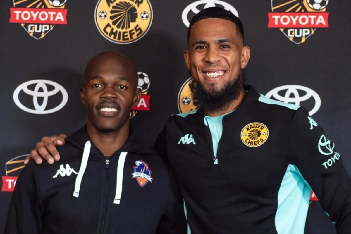Two men posing together at a sports event, one with a Chiefs crest, the other in a black jacket, smiling in front of a Toyota Cup backdrop.
