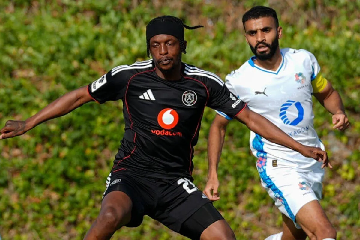 Two male soccer players sprinting on a grassy field, one in a black kit and the other in white, competing for the ball behind them in motion. Two male soccer players sprinting on a grassy field, one in a black kit and the other in white, competing for the ball behind them in motion.