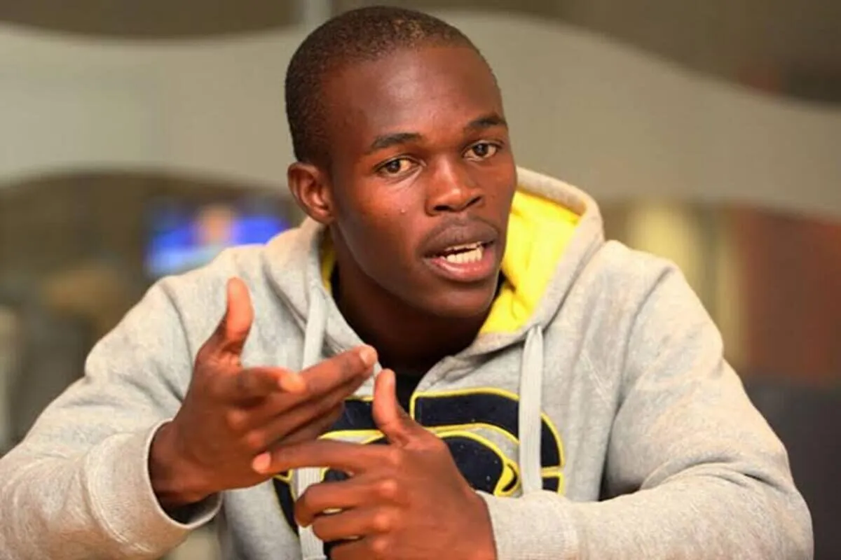 Young man in a gray hoodie speaks animatedly, using hand gestures during a discussion or interview.