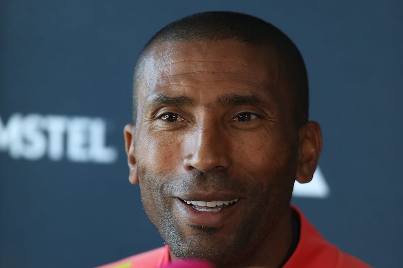 Close-up portrait of a smiling man with short hair in a red shirt against a dark blue backdrop Close-up portrait of a smiling man with short hair in a red shirt against a dark blue backdrop