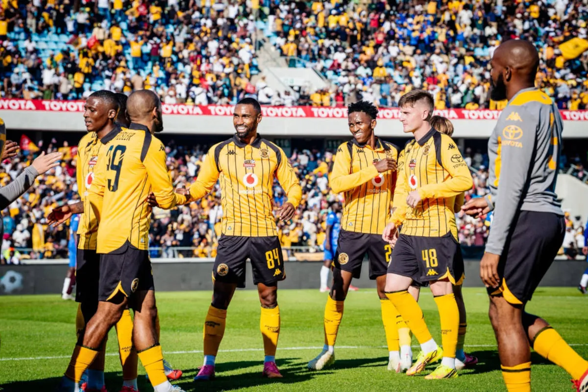 Soccer players in yellow and black striped jerseys celebrate on the field as fans cheer in the stands behind them.