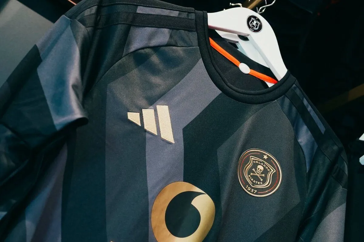 Dark striped sports jersey on a hanger with Adidas logo and Orlando Pirates crest visible. Dark striped sports jersey on a hanger with Adidas logo and Orlando Pirates crest visible.