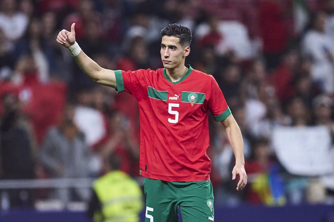 Soccer player in red jersey with number 5 giving a thumbs-up, crowd in the background; likely a national team match