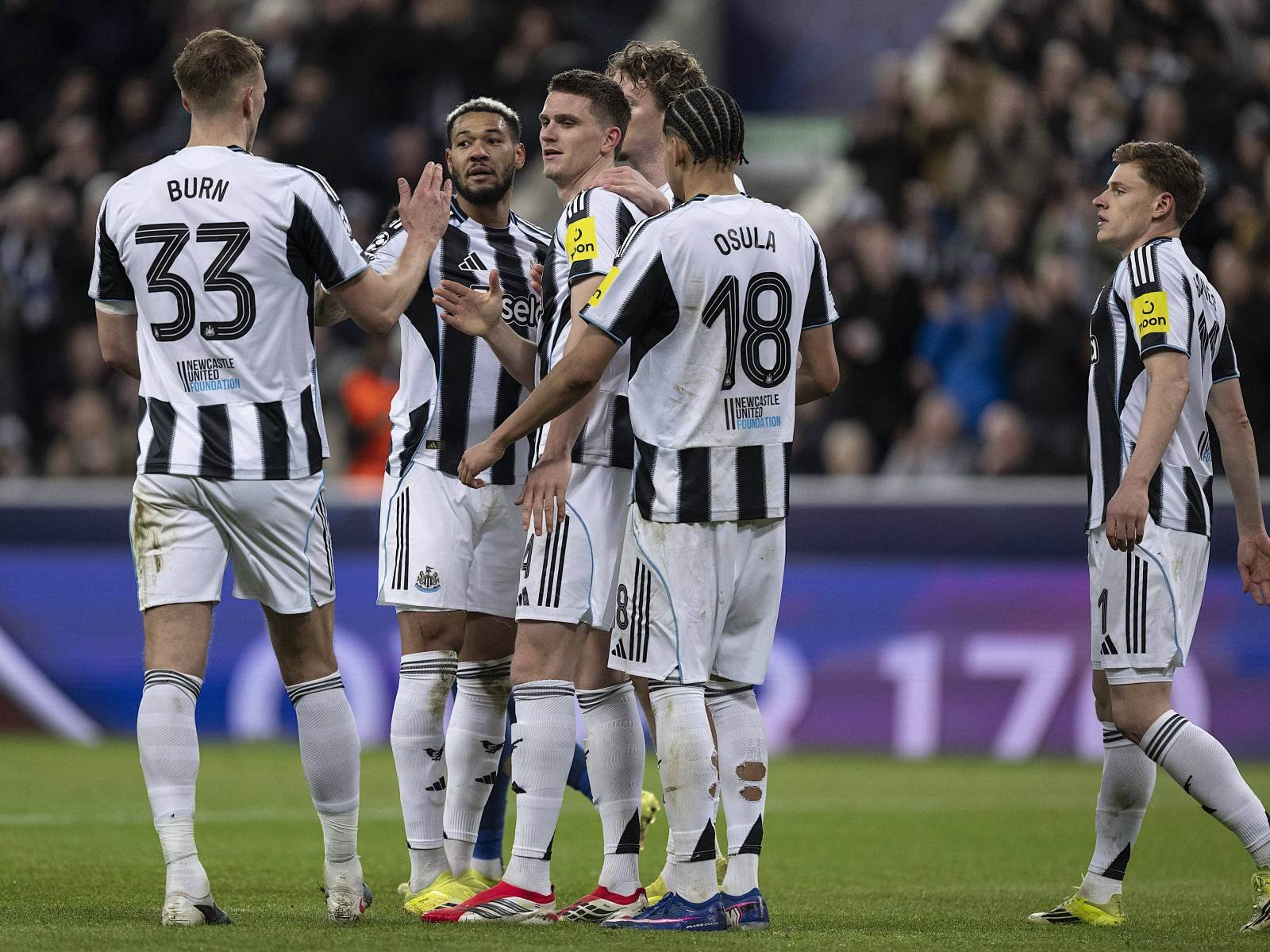 Newcastle United players in black-and-white striped kits huddle together on the pitch before a game.