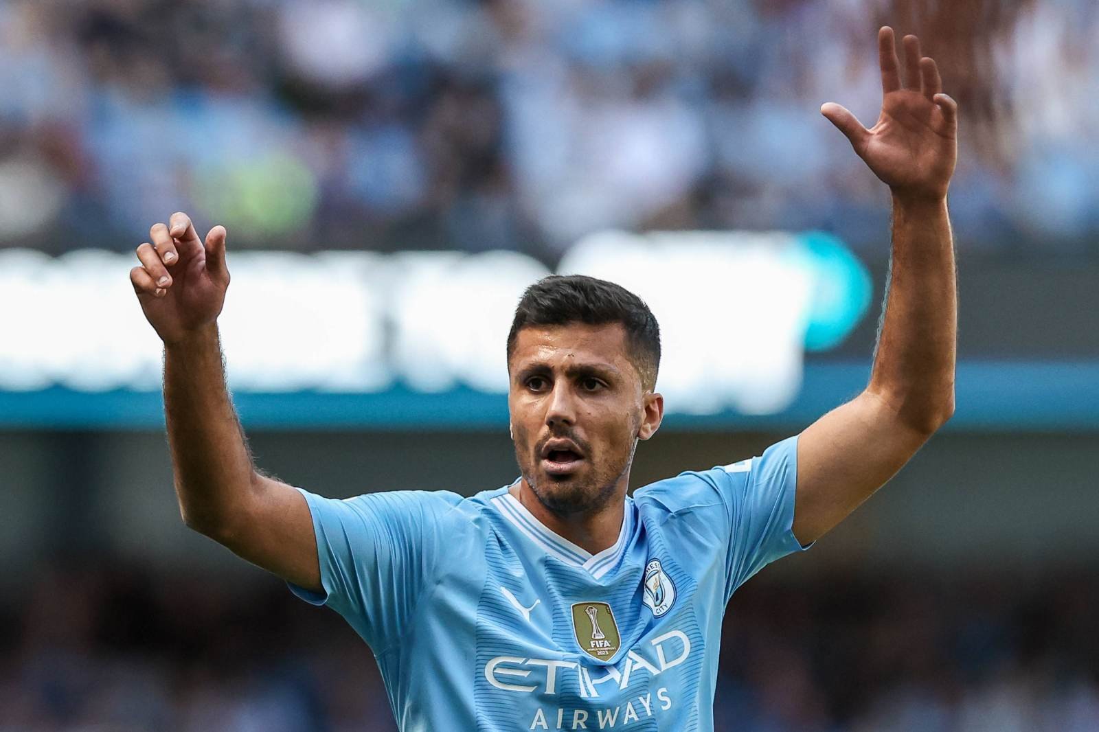 Manchester City player raises both arms in celebration on the pitch during a match veering toward a goal moment