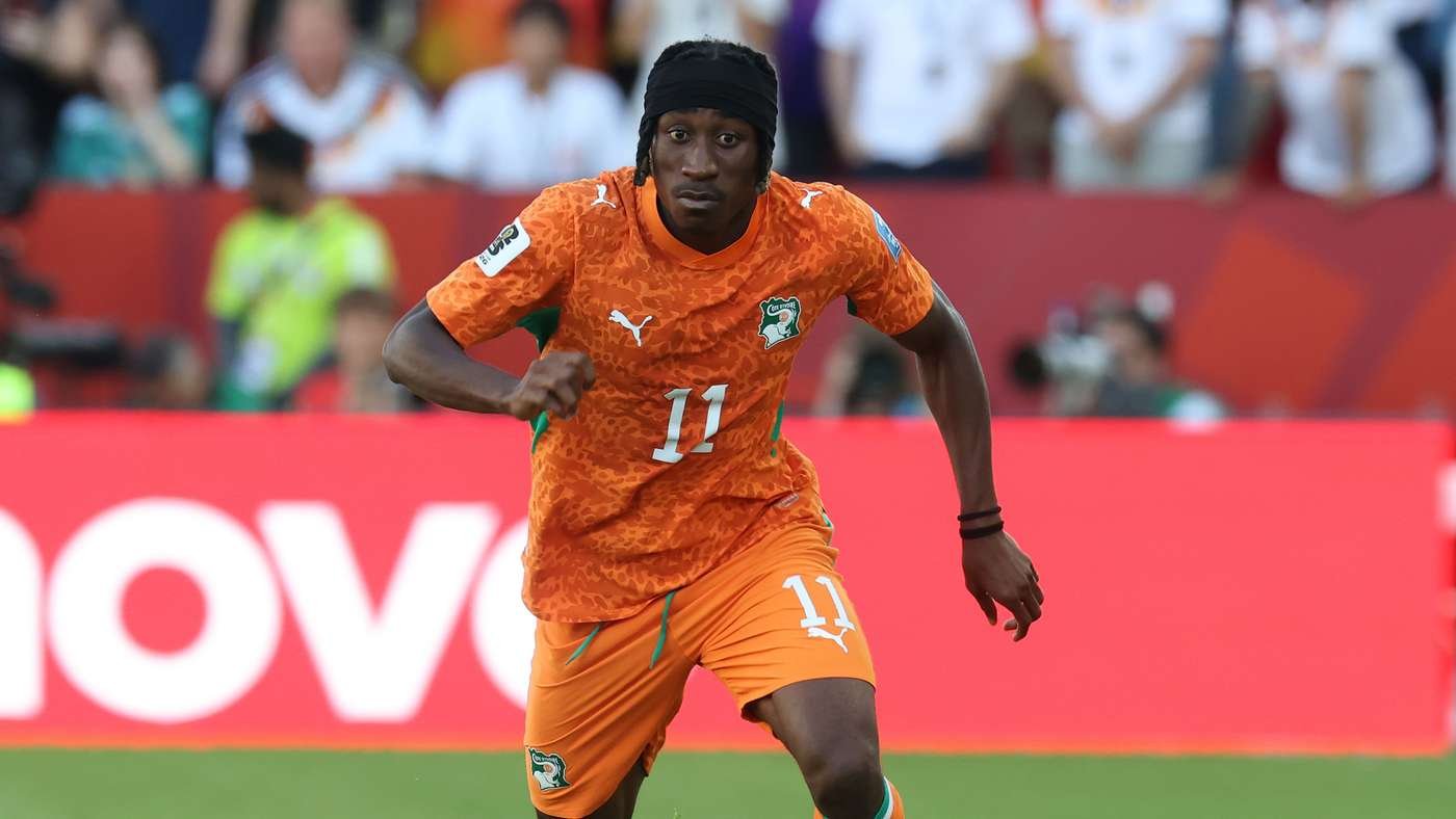 Soccer player in an orange kit with the number 11 sprinting on the field during a match, with a crowd in the background.