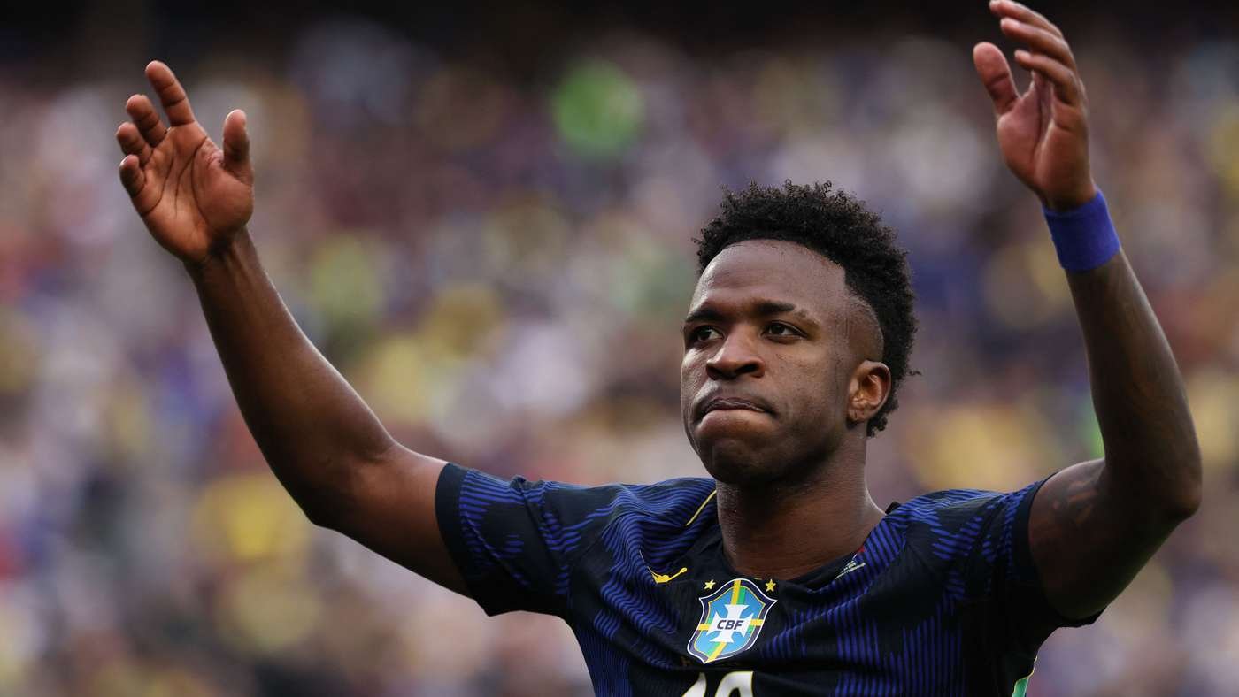 Soccer player in a blue Brazil jersey with arms raised in celebration on the field