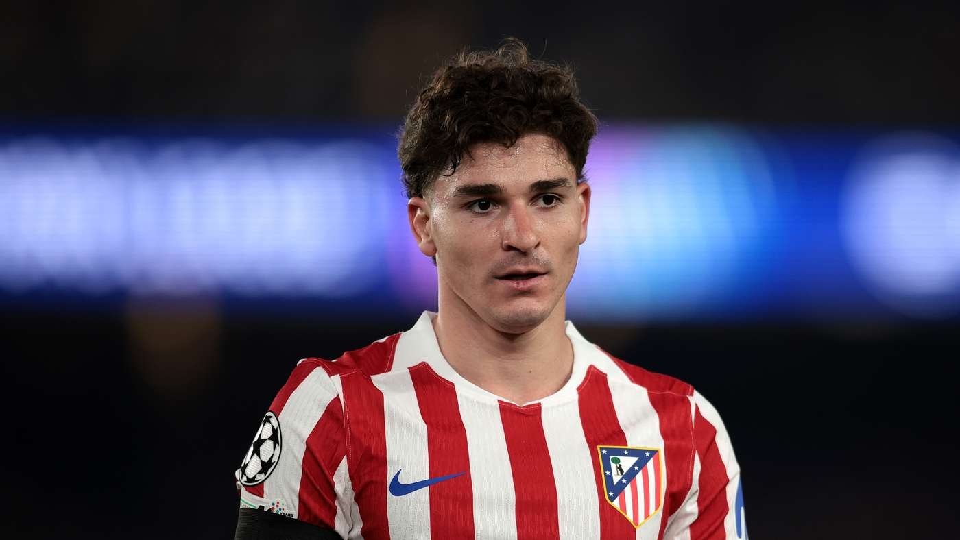 Soccer player in red-and-white striped Atlético Madrid jersey on the field, focused look before a match.