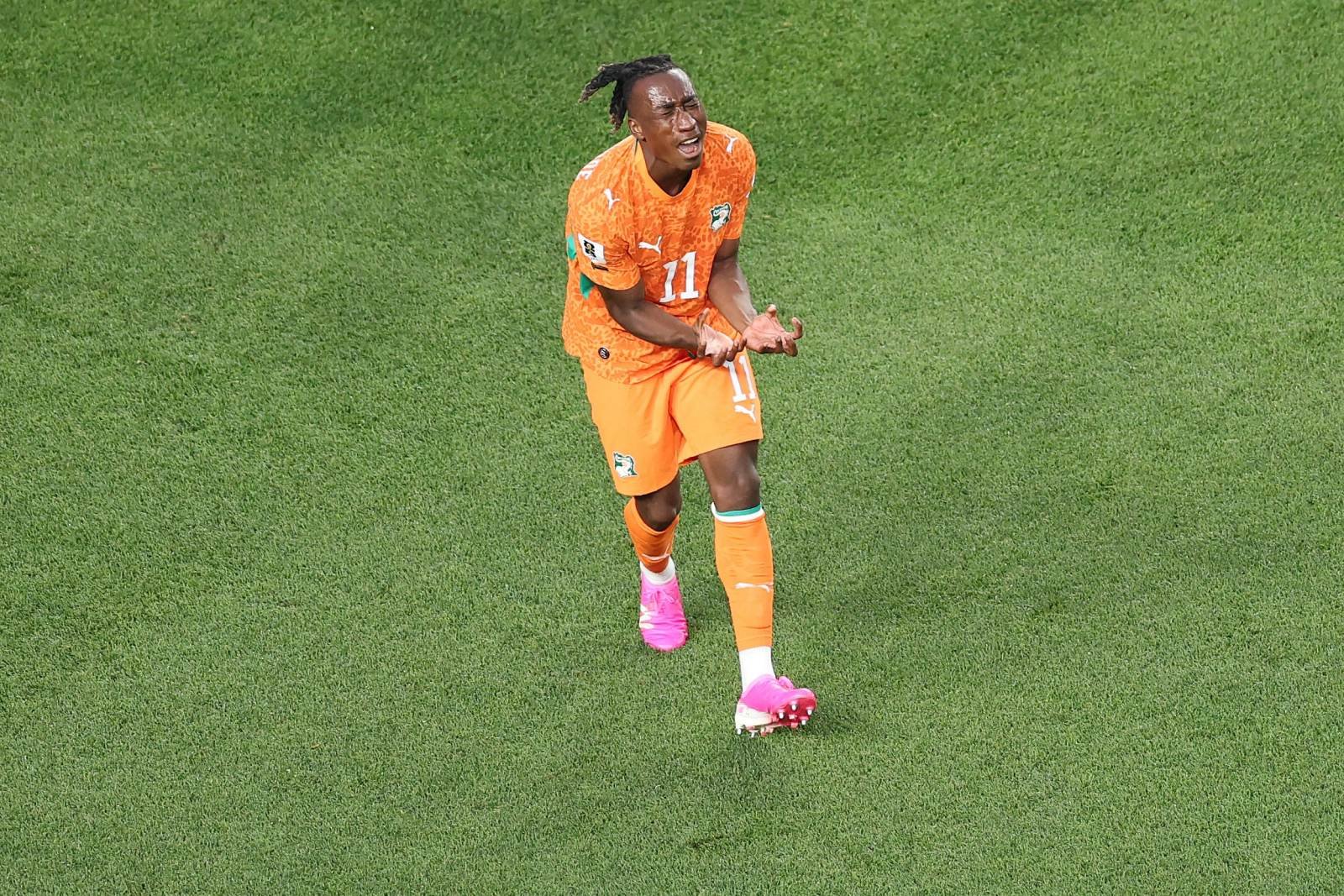 Soccer player in an orange jersey with number 11 sprinting on a green grass field wearing pink cleats.