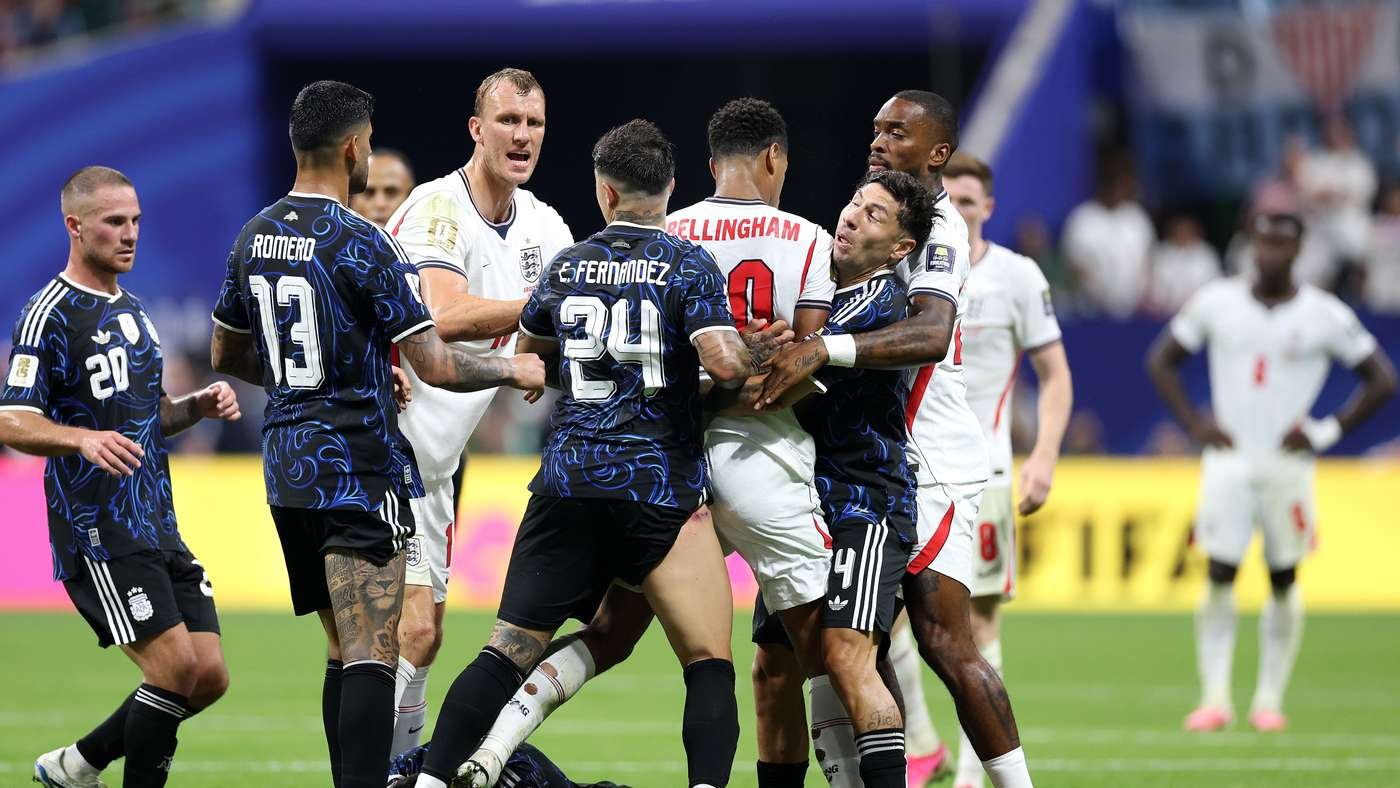 Soccer players from two teams grapple in a crowded moment on the pitch during a match.
