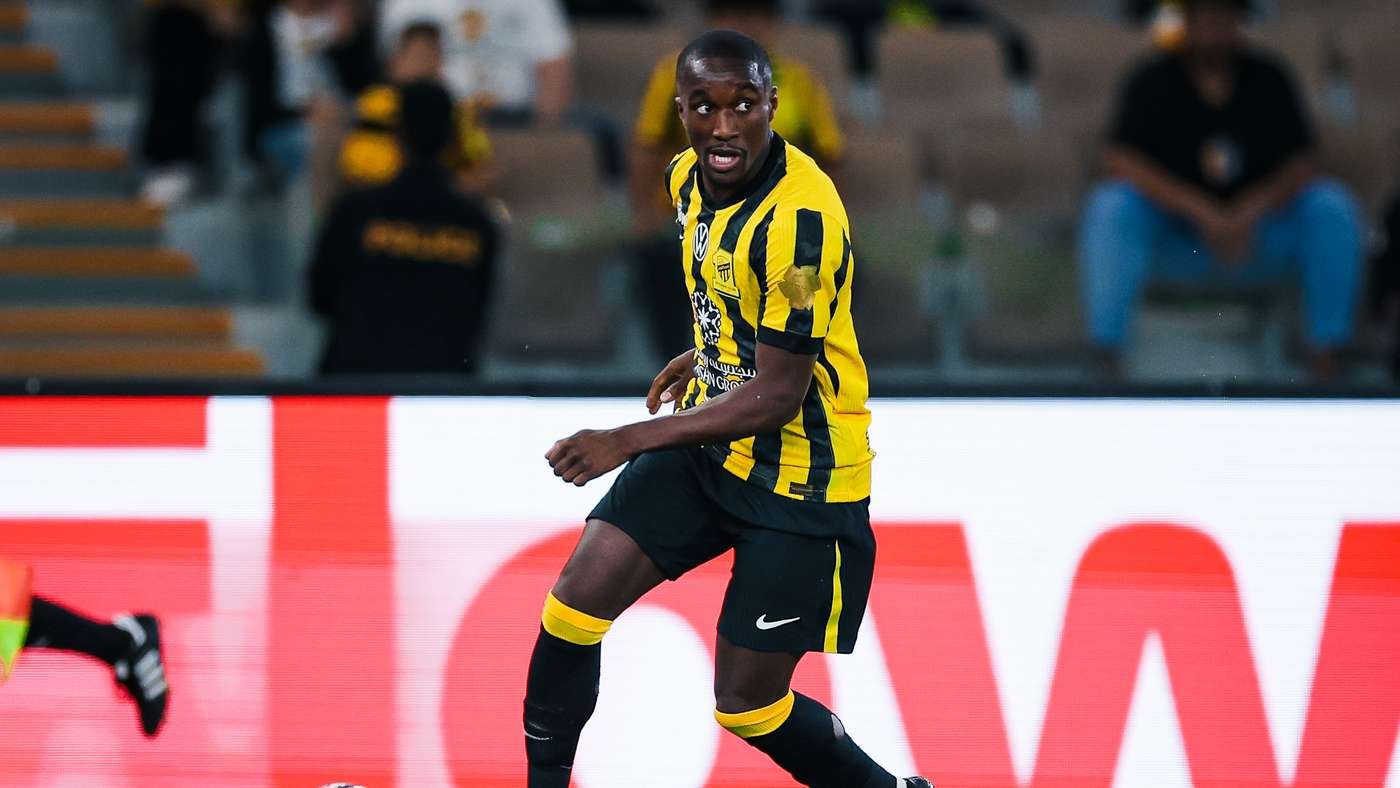 Soccer player in a yellow and black striped jersey runs on the pitch during a match.
