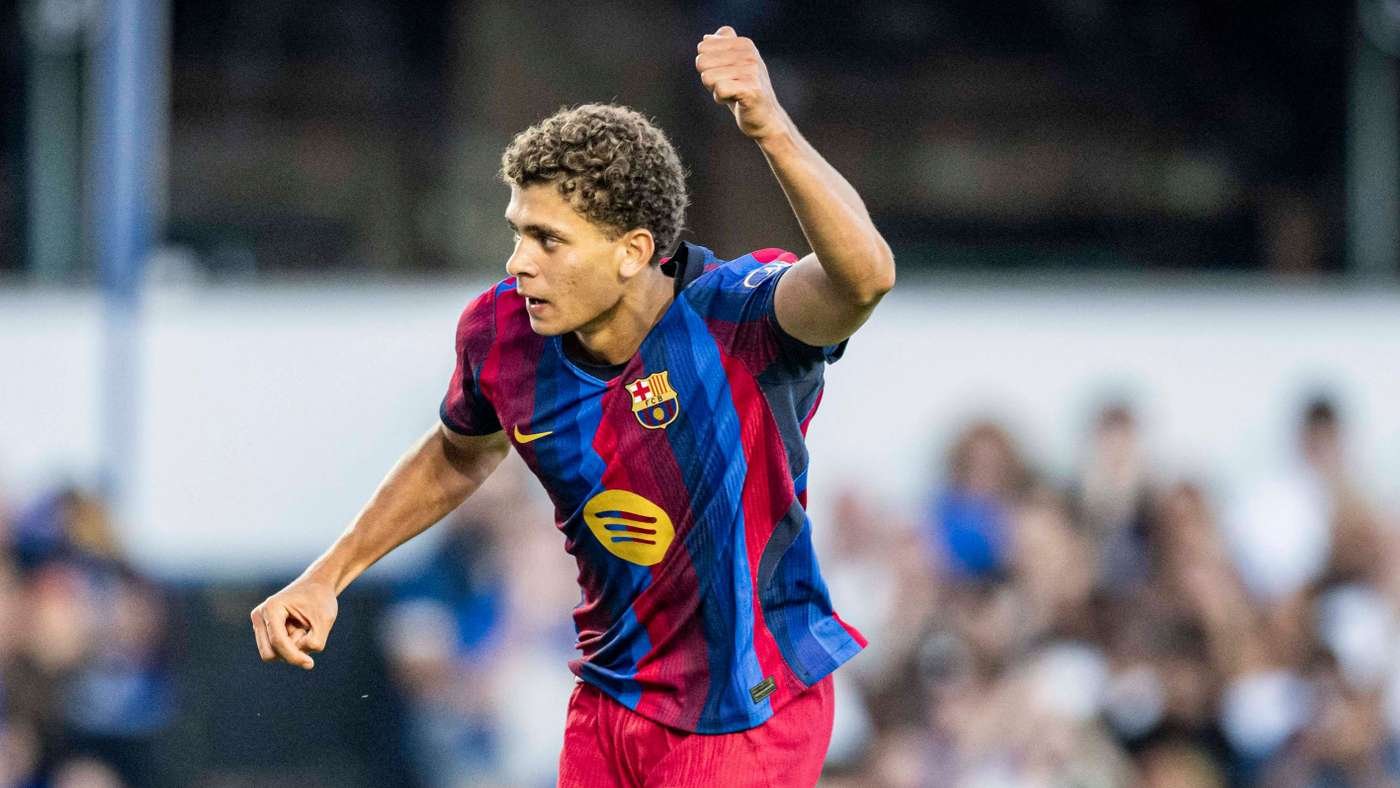 Soccer player in FC Barcelona kit celebrating with a raised fist on the field.