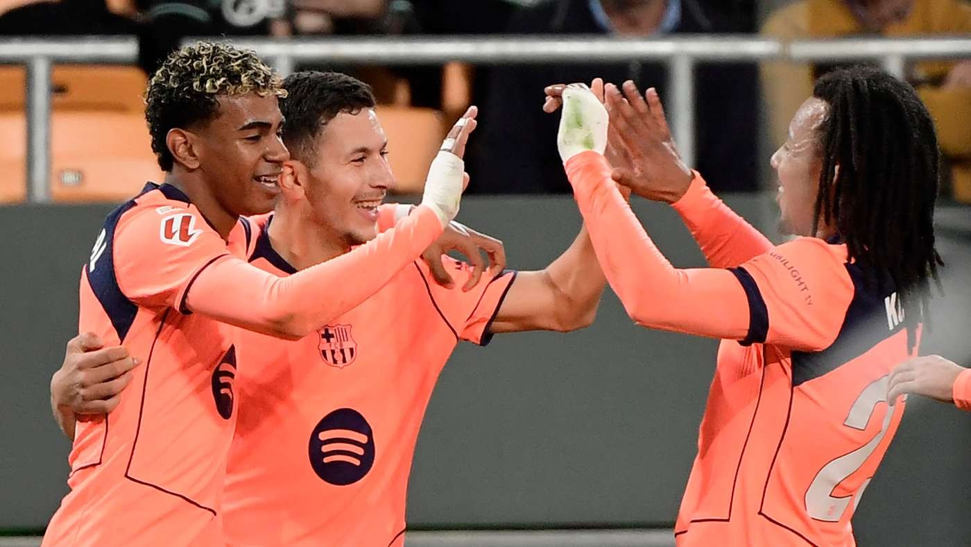 Three soccer players in bright pink jerseys celebrate with a high-five on the field.