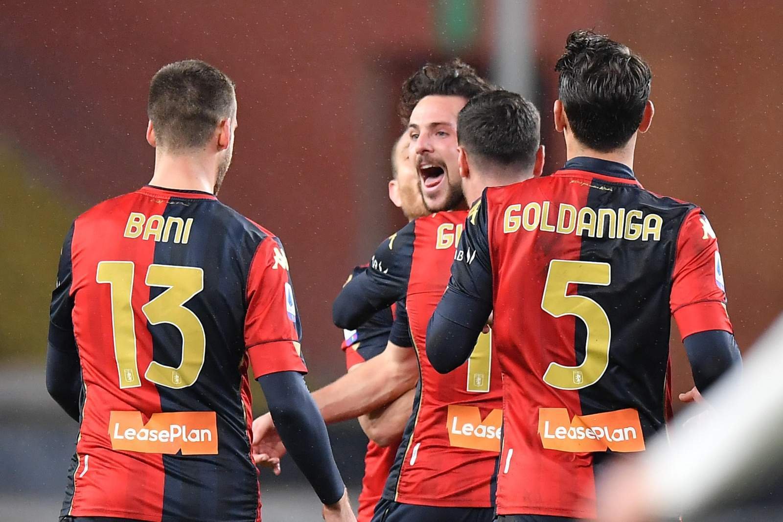 Soccer players in red-and-black uniforms celebrate, backs to camera, numbers 13 and 5 visible, Sponsor LeasePlan on shorts.